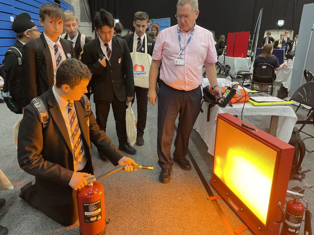 A student is shown how to put out a fire using an interactive display