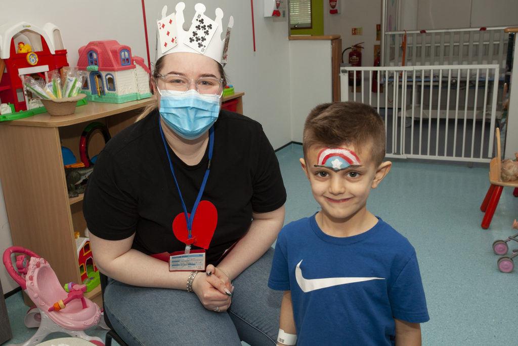 A picture of staff member with patient. The patient has had a Captain America shield painted on their forehead. 